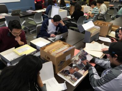 Students read from files drawn from archival boxes