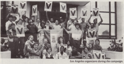 Grainy black and white photo of a group of young (ish) men and women. In the center, they hold a banner reading "L.A. Jobs with Peace", Many others in the photo are displaying signs with a large "V" on them (signs also say "Register to Vote here") or making a V sign with their fingers. They are posing outside the entrance of a building. In the bottom corner, the photo is captioned "Los Angeles organizers during the campaign."