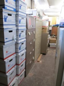 stacks of bankers boxes next to large filing cabinets in a basement